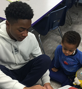 A sweet older student helping a younger in the classroom