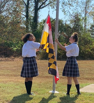 Two happy middle school girls raising the school flag