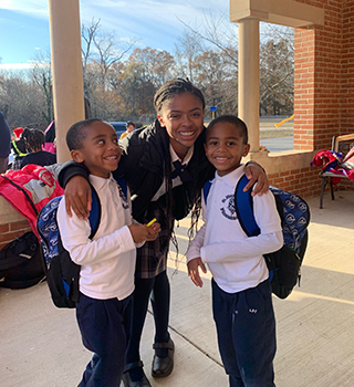 Three happy students posing for the camera outside the school building