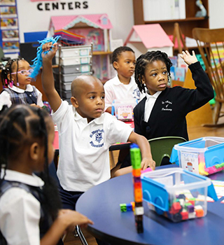 Two students in a classroom raising their hands