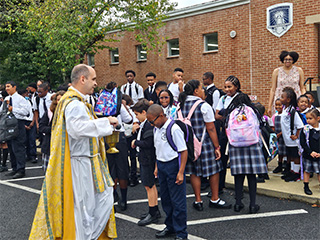 Reverend sharing holy water with students outside
