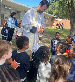 Reverend sharing holy water with students outside