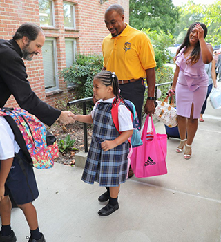 Families greeted by Rev. Baer coming to school